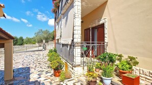 A building with a tiled patio, potted plants, and a balcony with a metal railing. - Apartment 539 (Medulin)