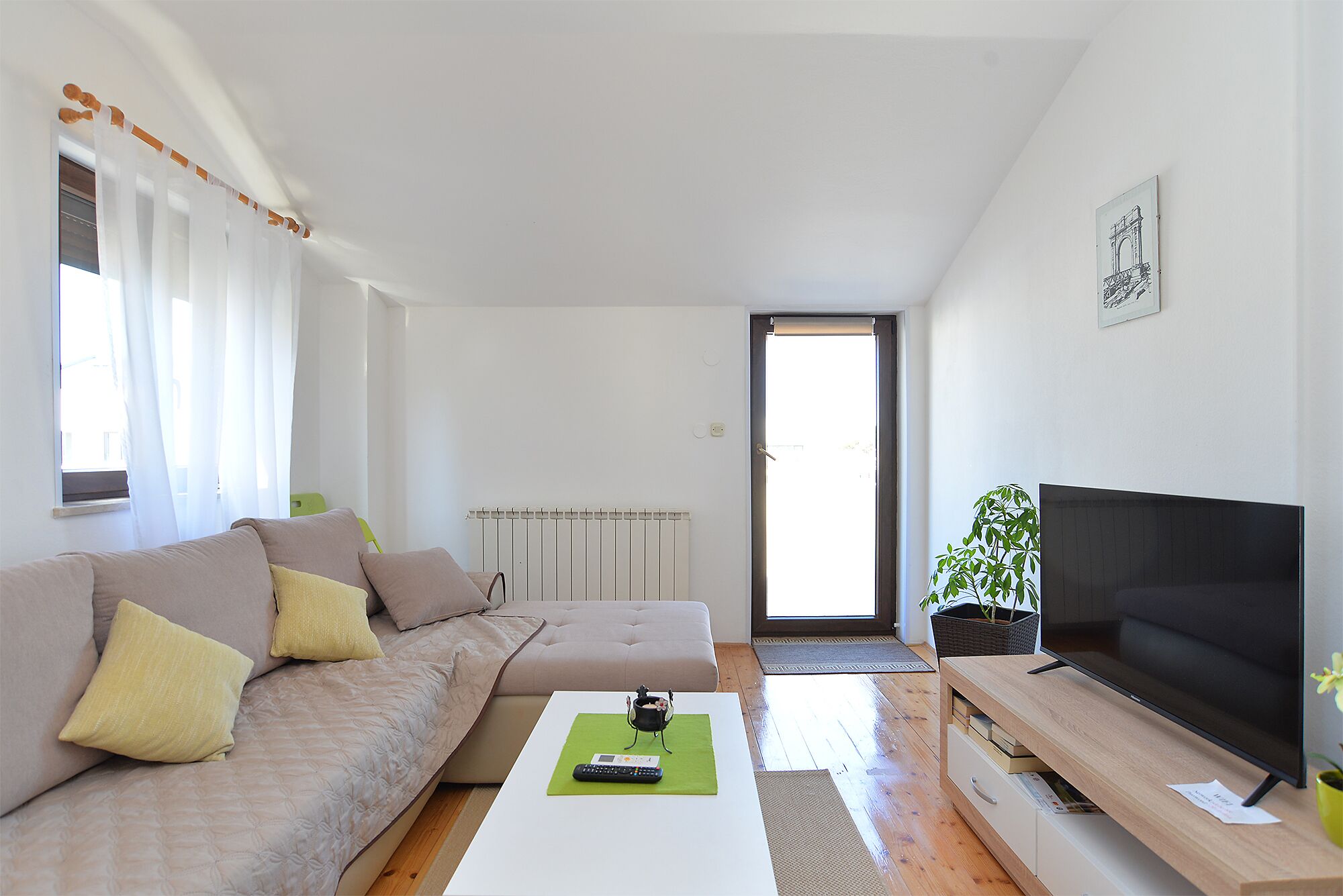Un salon avec un canapé, une table basse, un téléviseur et un radiateur.