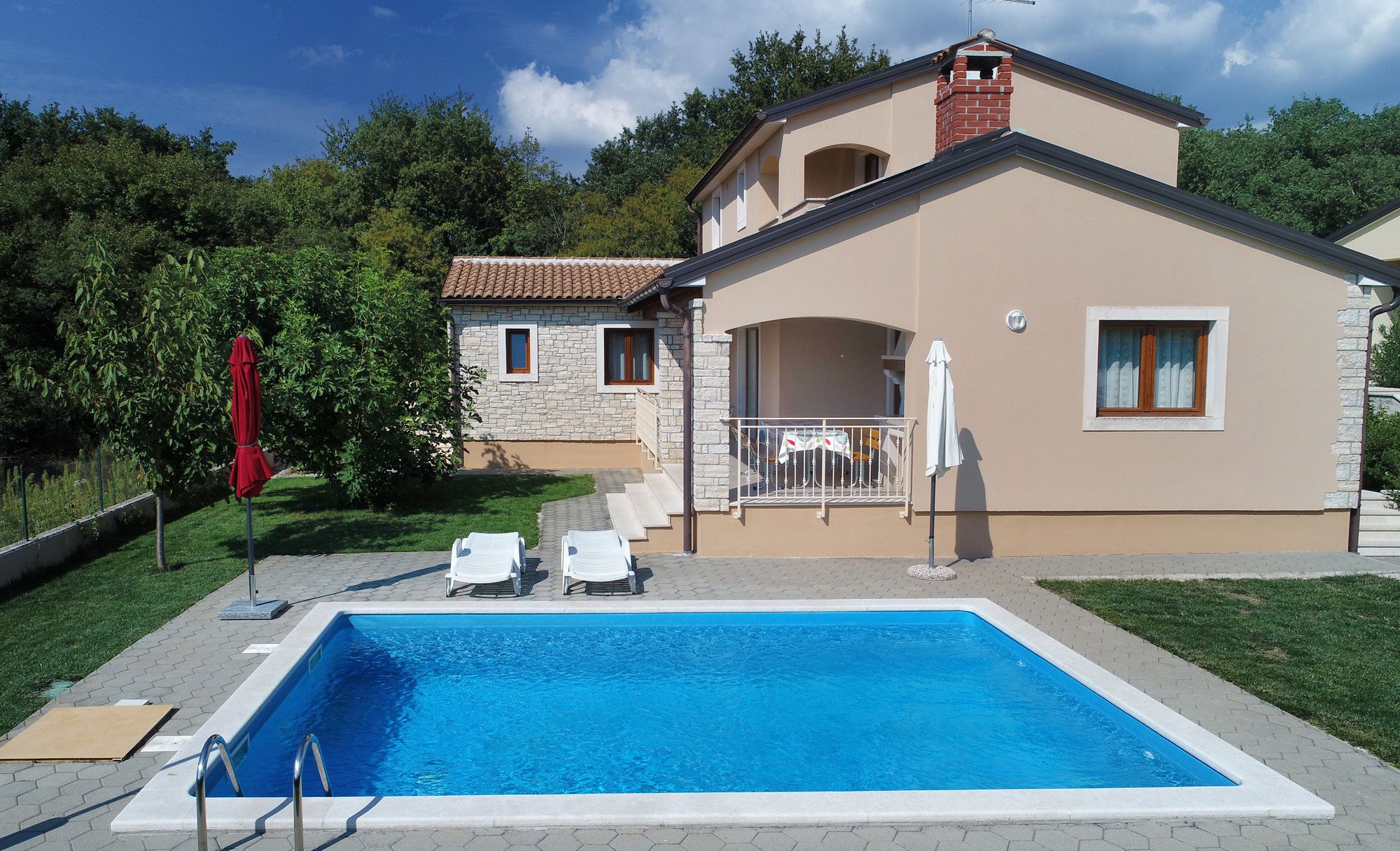 A two-story house with a swimming pool, a small detached building, and a garden.