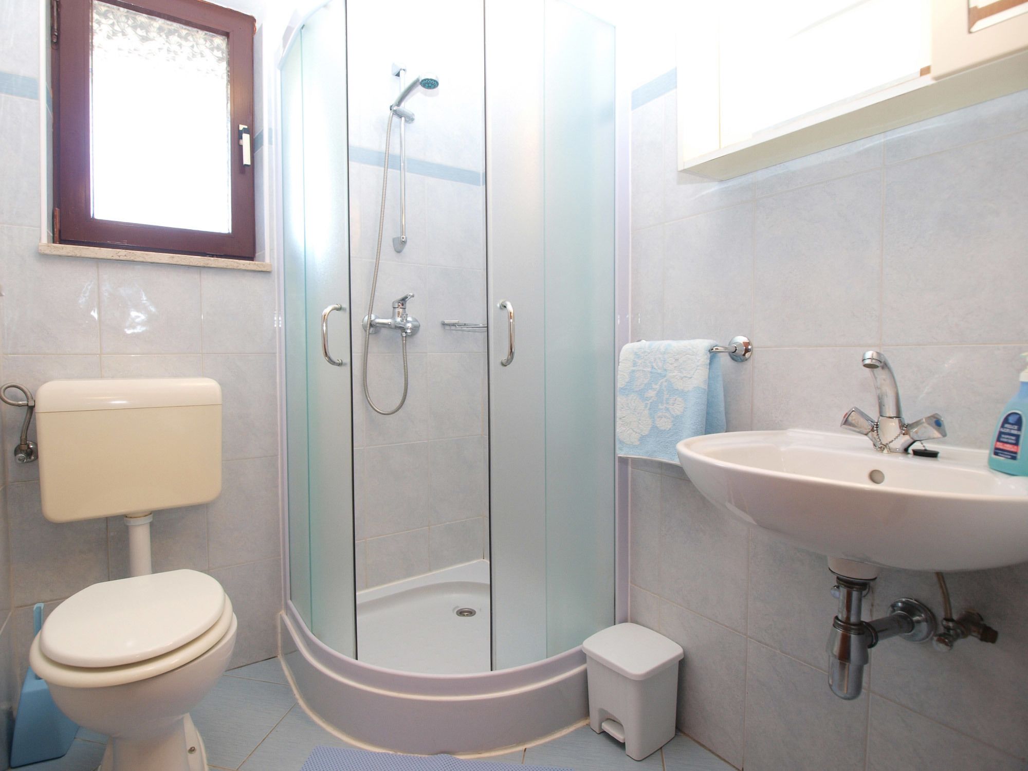 Une salle de bain avec une douche à parois de verre, des toilettes et un lavabo.