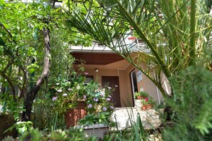 A residential building with a front entrance, surrounded by lush greenery and flowering plants. - Apartment 604 (Pula)