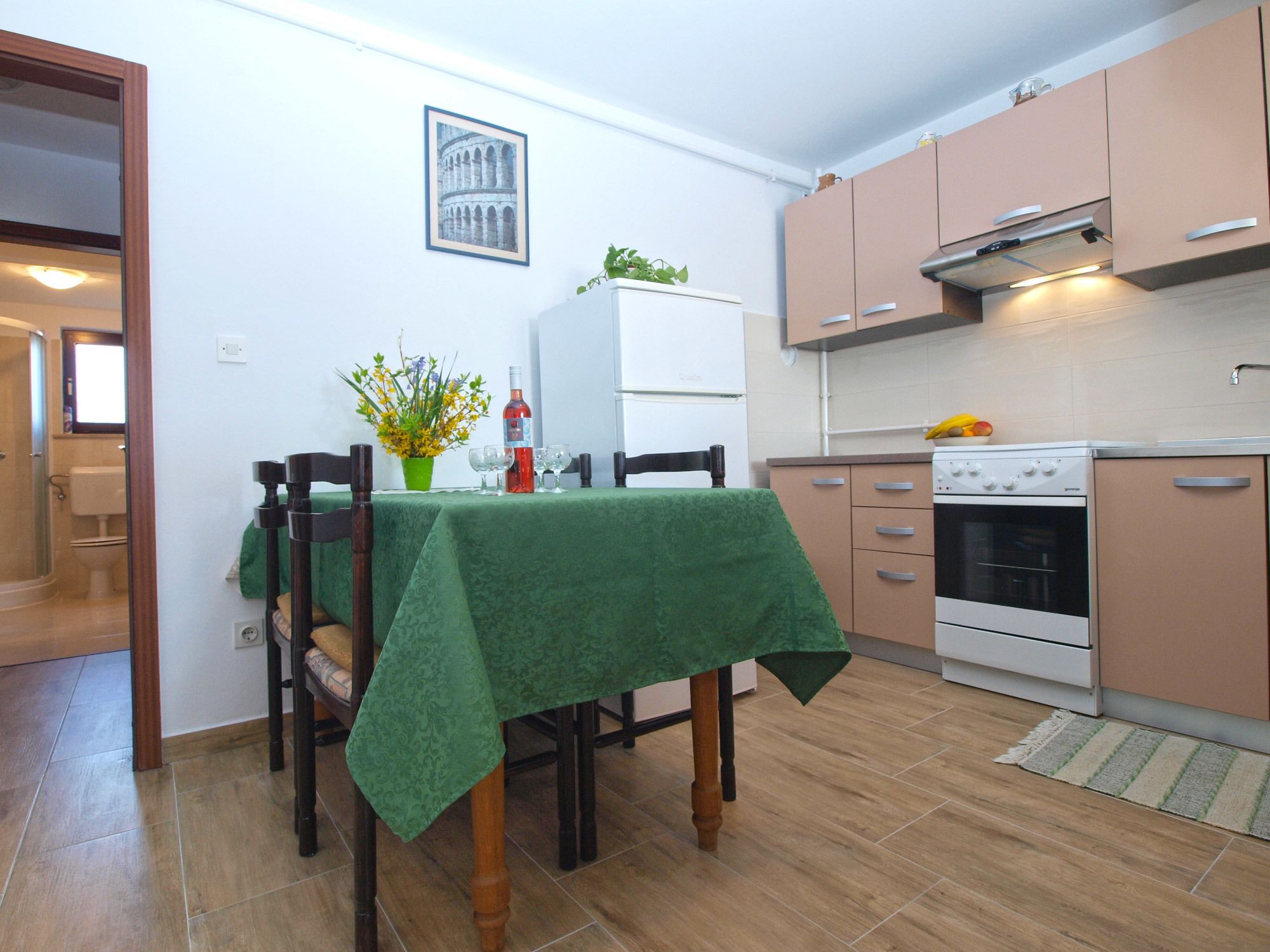A compact kitchen with a dining table, chairs, a refrigerator, an oven, and a sink.