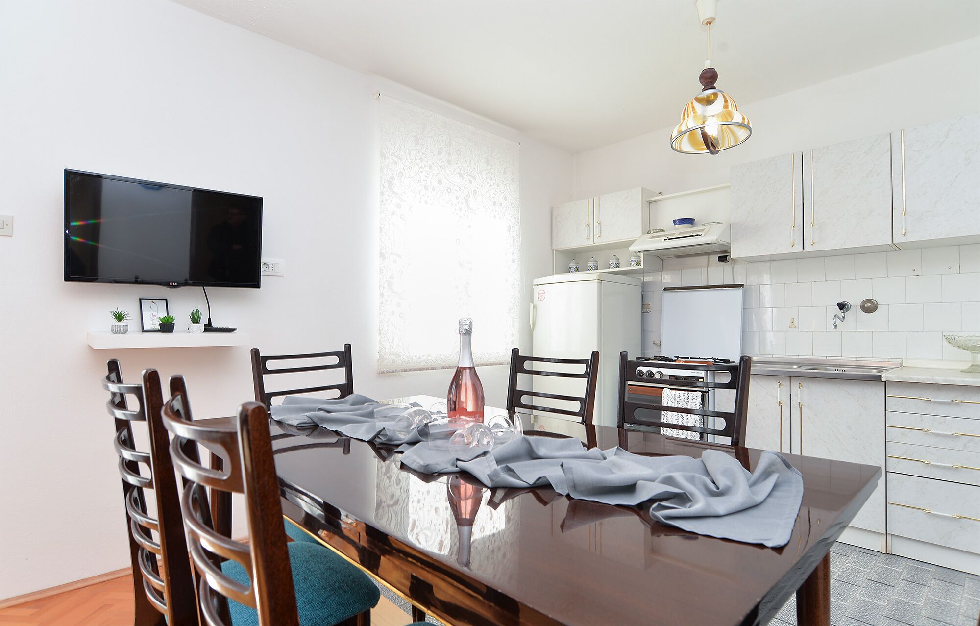 Un coin repas avec une table en bois, des chaises et un téléviseur fixé au mur.