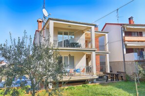 A two-story residential building with a balcony on the upper floor and a patio area with outdoor furniture. - Apartment 621 (Rovinj)