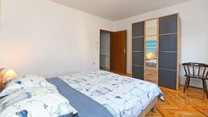 Ett sovrum med en säng, en trästol, en garderob med en spegel och en taklampa.
