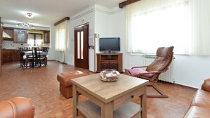 A living room with a wooden table, leather sofa, and a TV on a wooden stand. - Apartment 622 (Rovinj)