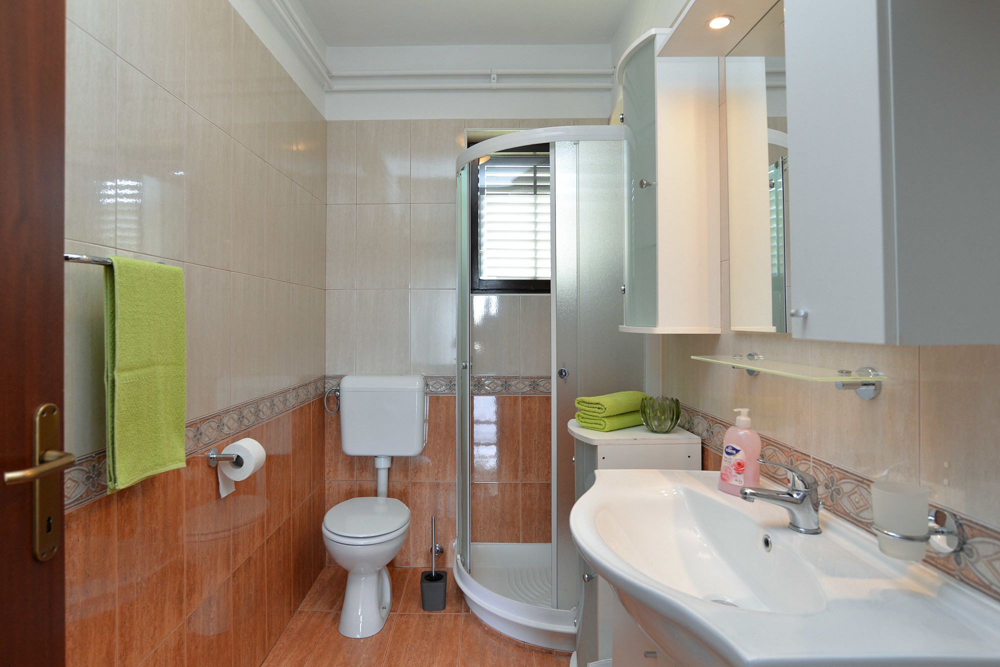 A bathroom with a toilet, shower, and sink.