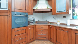 A kitchen with wooden cabinets, a built-in oven, a microwave, and a sink. - Apartment 622 (Rovinj)