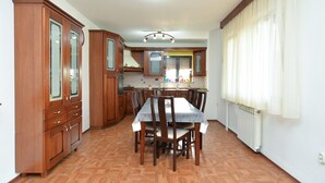 A spacious kitchen with wooden cabinets, a dining table, and chairs. - Apartment 622 (Rovinj)