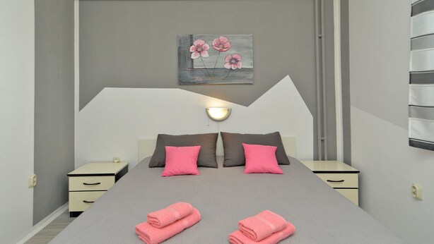 A modern bedroom with a large bed, two bedside tables, and a wall-mounted light fixture. - Apartment 622 (Rovinj)