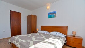 Un dormitorio con cama, armario de madera, mesita de noche y una pintura de playa.