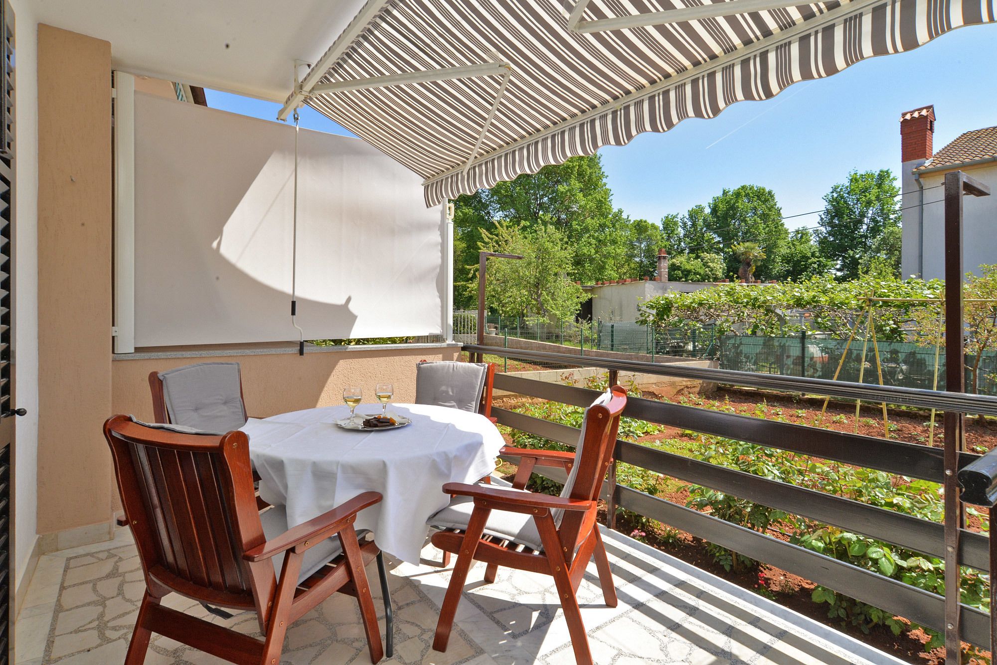 A patio with a table and chairs, a white tablecloth, and a striped awning.