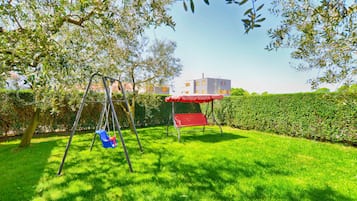 A grassy backyard with a swing set and a red canopy.