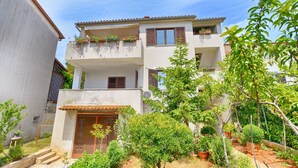 A two-story building with a balcony on the upper floor, surrounded by greenery and potted plants. - Apartment 640 (Pula)