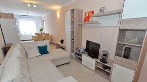 A modern living room with a white sofa, a flat-screen TV, and built-in shelving. - Apartment 640 (Pula)