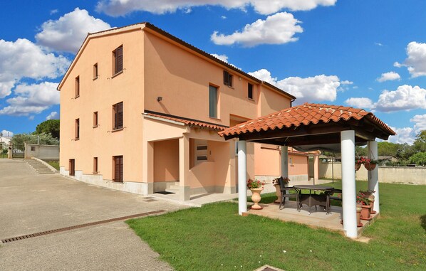 A two-story house with a tiled roof and a covered patio area with outdoor furniture.