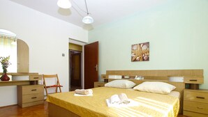 A bedroom with a large bed, wooden headboard, bedside tables, a desk with a chair, and a mirror. - Apartment 686 (Pula)
