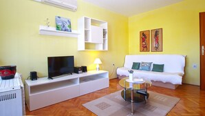 A living room with a white sofa, a glass coffee table, a TV, and a red bowl on a white cabinet. - Apartment 686 (Pula)