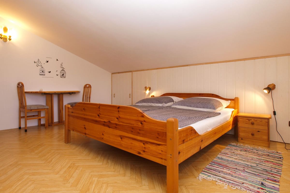 A bedroom with a wooden bed, a desk, and two chairs.