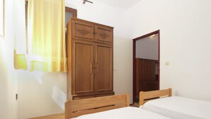 A bedroom with two single beds, a wooden wardrobe, and a mirror on the wall. - Apartment 695 (Pula)