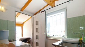 A compact kitchen with a sink, a window, and a door leading to another room. - Apartment 700 (Rovinj)