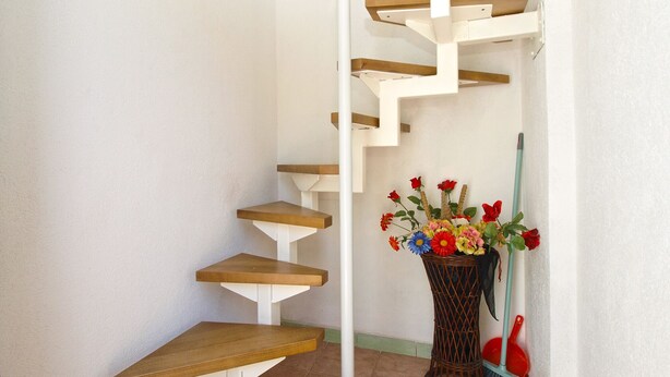 A staircase with wooden steps and white railings, leading to a landing with a wicker vase of flowers. - Apartment 700 (Rovinj)