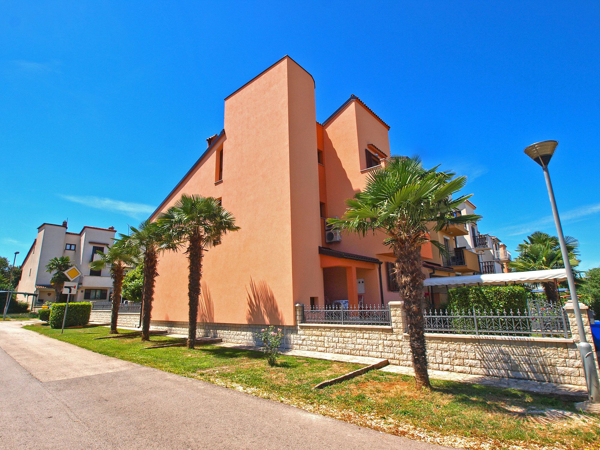 A building with a flat roof, a balcony, and a stone base.