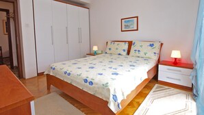 A bedroom with a bed, bedside tables, a wardrobe, and a small painting on the wall. - Apartment 711 (Fazana)