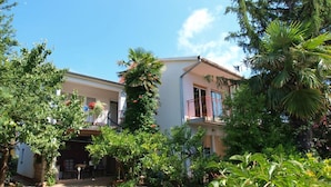 A two-story residential building with a balcony, surrounded by lush greenery and trees. - Apartment 712 (Medulin)
