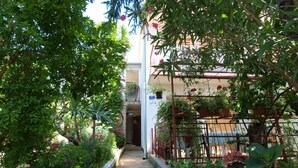A narrow stone pathway leading to a building with a metal fence and potted plants. - Apartment 712 (Medulin)
