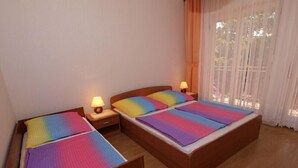 A room with two beds, each with a rainbow-patterned bedspread, wooden headboards, and bedside lamps. - Apartment 712 (Medulin)