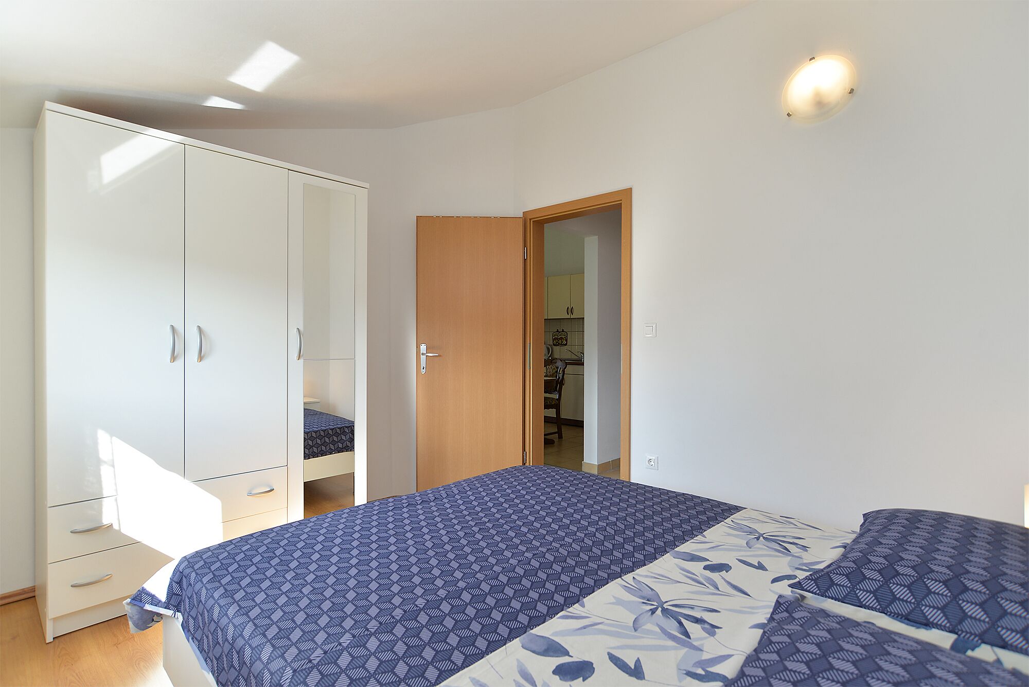 A bedroom with a bed, wardrobe, and a door leading to a bathroom.