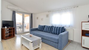 Ein Wohnzimmer mit einer Couch, einem Fernseher, einem Couchtisch und einem Schrank.