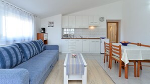 Ein kompakter Wohnbereich mit Sofa, Esstisch und Küchenzeile.
