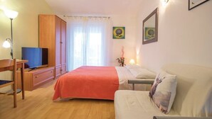 A bedroom with a bed, a sofa, a TV, and a desk.