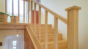 A wooden staircase with a handrail, leading to a landing with a door and a light fixture.
