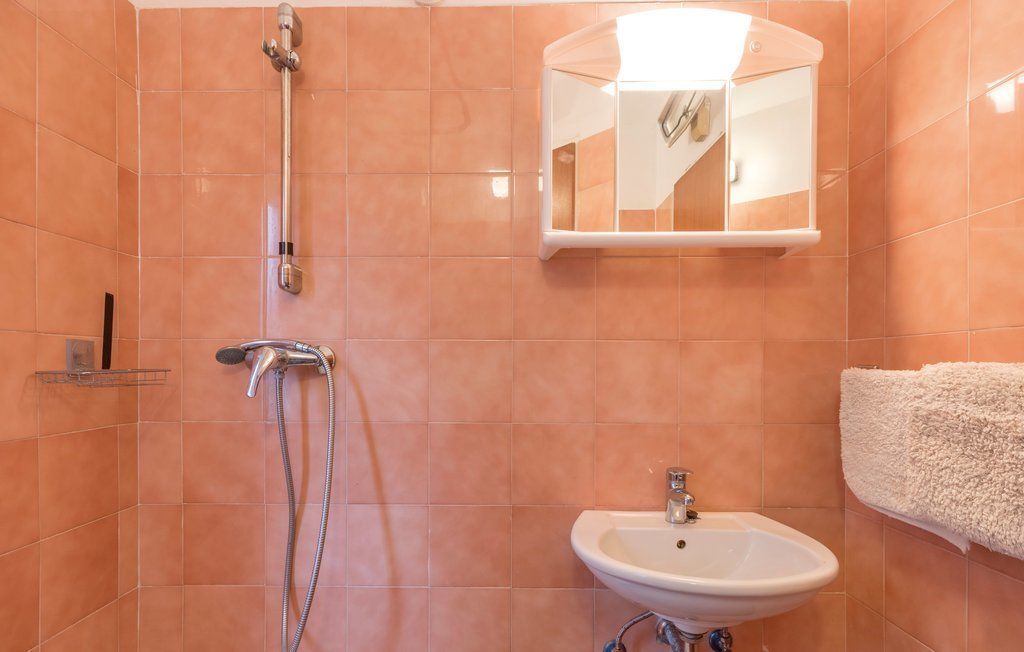 Un bagno con doccia, lavandino e porta asciugamani.