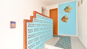 A staircase with a blue perforated partition, a wooden door, and two fish wall decals. - Apartment 725 (Fazana)