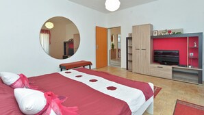 A bedroom with a bed, a round mirror, a wardrobe, a TV, and a red accent wall. - Apartment 725 (Fazana)