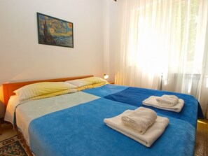 Ein Hotelzimmer mit Bett, zwei Handtüchern, einem Gemälde und einem Fenster mit Vorhängen.