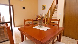 Un comedor con mesa de madera, sillas y un florero con flores.