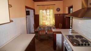 A kitchen with a stove, cabinets, and a dining table with chairs. - Apartment 731 (Pula)