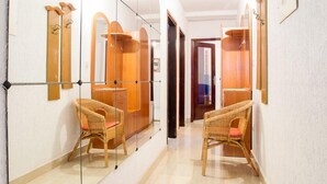 Un couloir aux murs recouverts de miroirs, avec des meubles en bois et une porte donnant sur une autre pièce.