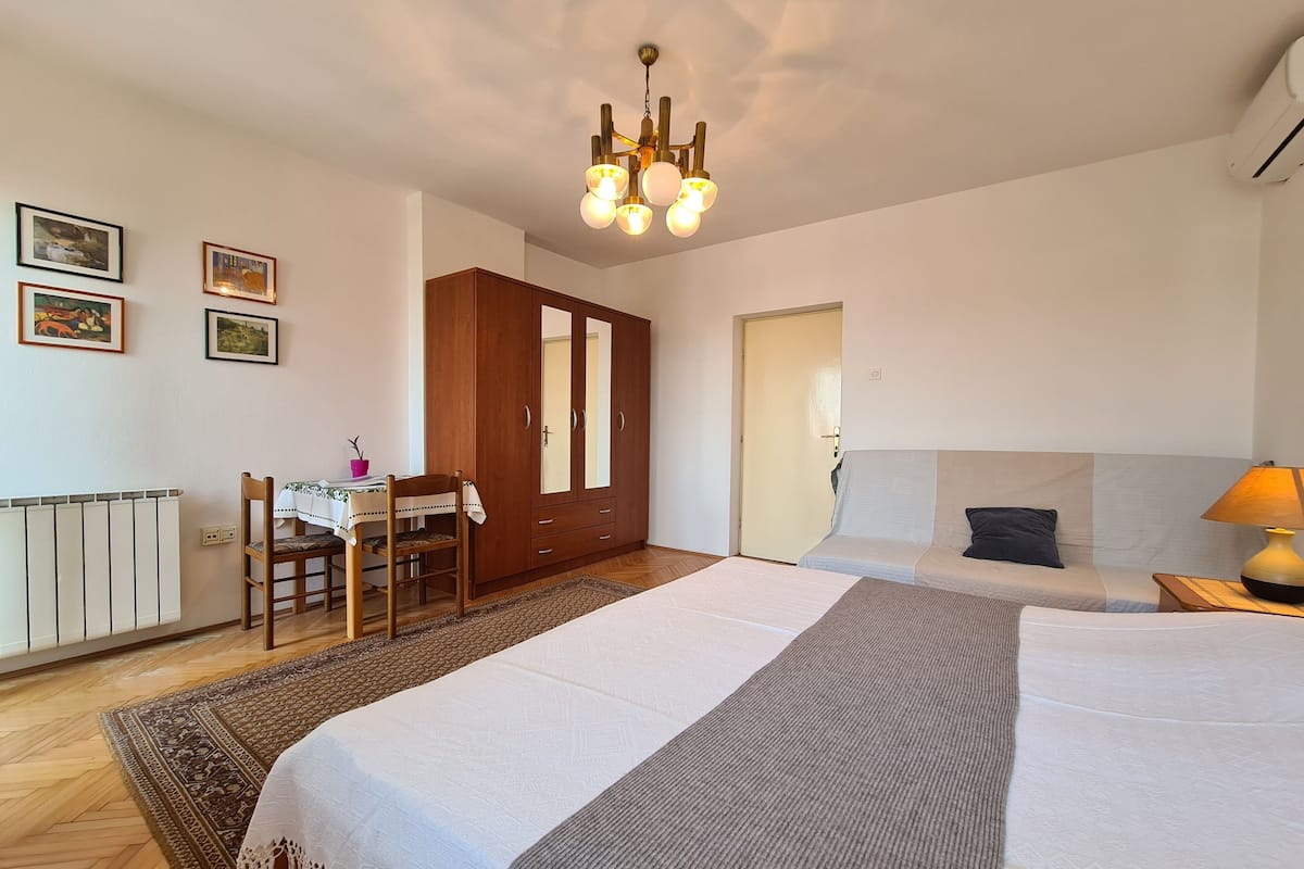 A bedroom with a bed, a desk with a chair, a wardrobe, and a door.
