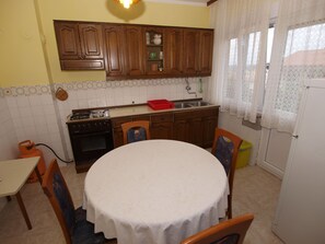 Cocina compacta con armarios de madera, estufa a gas y una mesa de comedor con sillas.
