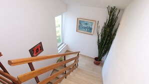 A staircase with wooden handrails, a potted plant, and a framed picture on the wall. - Apartment 761 (Medulin)