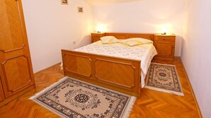 A bedroom with a wooden bed, two bedside tables with lamps, a nightstand, a patterned rug, and a wooden wardrobe. - Apartment 761 (Medulin)