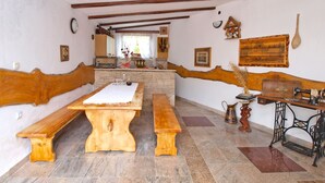 A rustic dining area with wooden benches and a central table, a vintage sewing machine, and a stone wall. - Apartment 772 (Fazana)