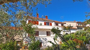 A white building with red shutters and a stone wall in front. - Apartment 772 (Fazana)