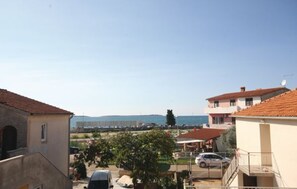 A residential area with buildings, a parked car, and a clear view of the sea. - Apartment 773 (Fazana)